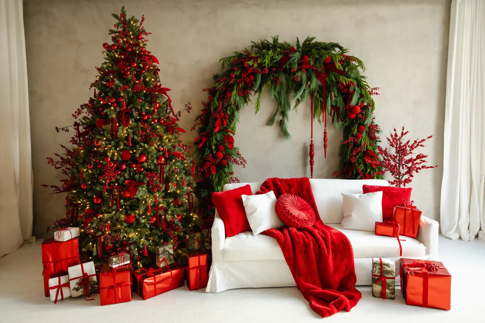The Bordeaux Berry set in Preto Loft's Solarium: a decorated tree, an evergreen and berry garland arch over a white couch, and red-wrapped gifts