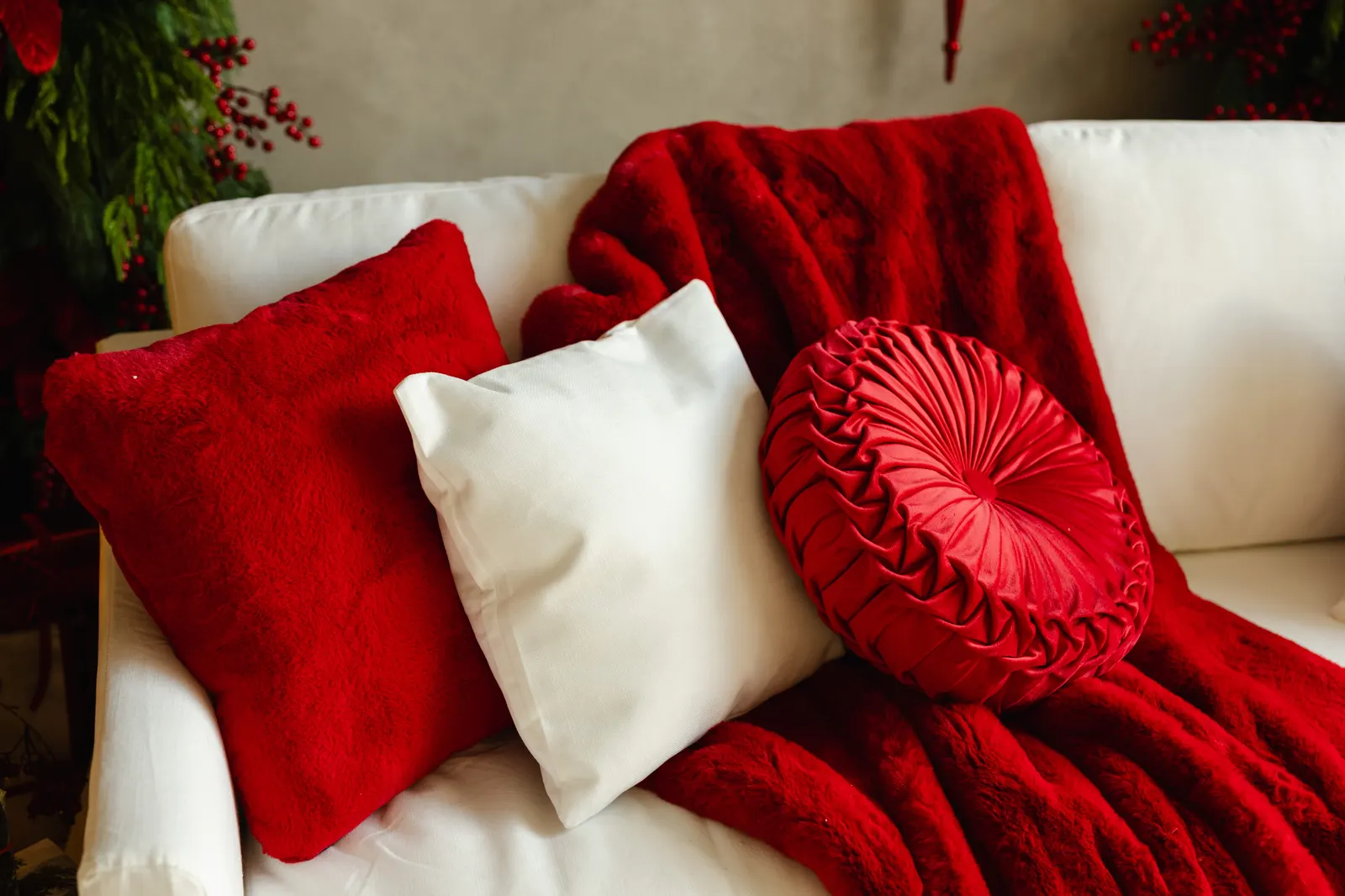 The white couch on the Bordeaux Berry set, with red and white cushions, a round pleated red pillow and a red faux-fur throw