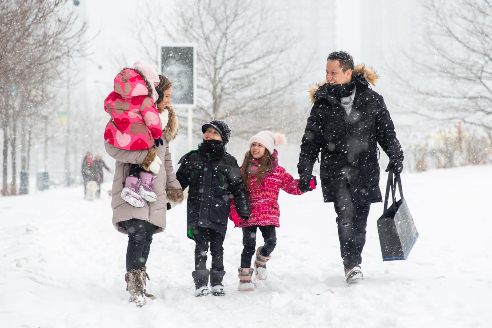 A family of five walking through falling snow at CityPlace